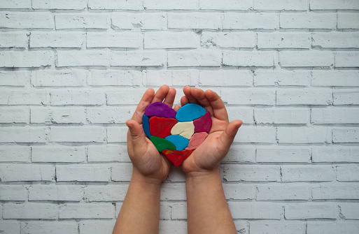 Child's hands holding a heart on white background with text space.