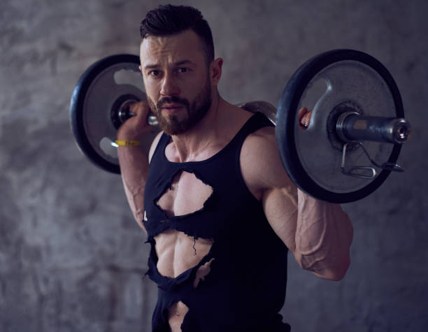 istock A man in a shadow with barbell on his shoulders. 938065278