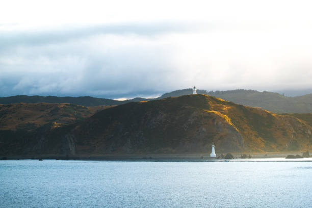 Landscape of the Mountain with lighthouse and sea with cloudy in the morning. Landscape of the Mountain with lighthouse and sea with cloudy in the morning. View from the ferry to  South Island, New Zealand. picton new zealand stock pictures, royalty-free photos & images