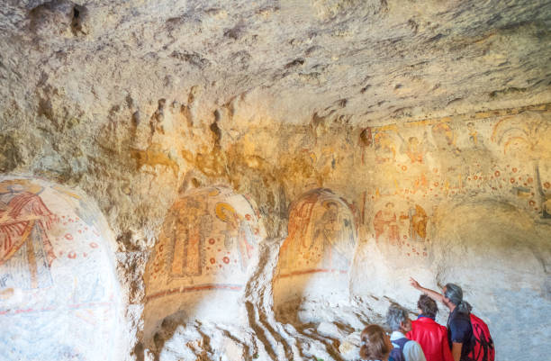 Matera, the town of the Sassi, prehistoric troglodyte settlements Matera, Italy - may 5, 2017: Visitors lloking at the ancient frescoes in the crypt of the Original Sin crypts stock pictures, royalty-free photos & images