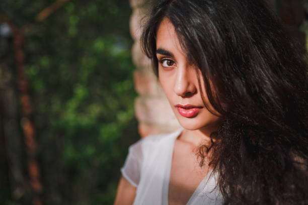 istock Lovely brooding brunette girl with long hair in a blooming spring garden under the warm rays of the sun. Close up. 938070844