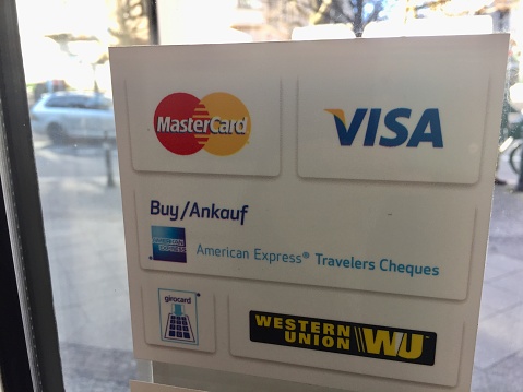 Berlin, Germany - February 2, 2018: Logos of Mastercard, Visa, American Express Travelers Cheques, Western Union on a window sticker