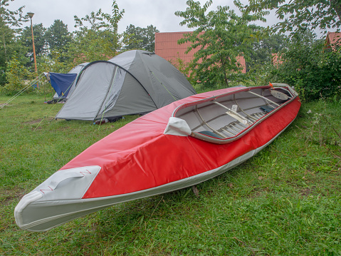 Red folding kayak and the tent on the grass