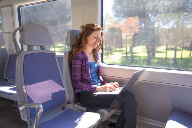 istock smiling woman in train typing on laptop computer 938093232