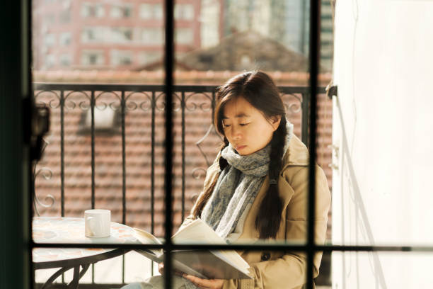 istock girl drinking coffee and reading book on balcony 938093324