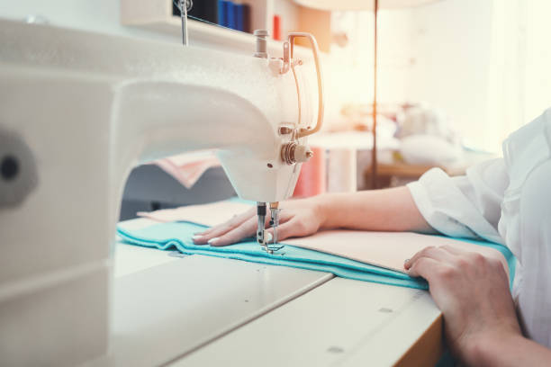 sewing machine and female hands of close up view. young dressmaker sew and working with cloth in design studio. small business - sewing tailor sewing machine women imagens e fotografias de stock