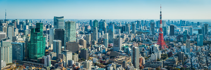 Aerial panoramic view across the skyscrapers and landmarks of downtown Tokyo, from the distant soaring spire of the Skytree, across the crowded cityscape of Ginza, Shimbashi and Minato to the iconic red lattice of Tokyo Tower, Japan.