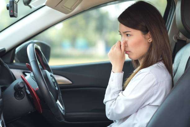 Young woman holding her nose because of bad smell in car stock photo
