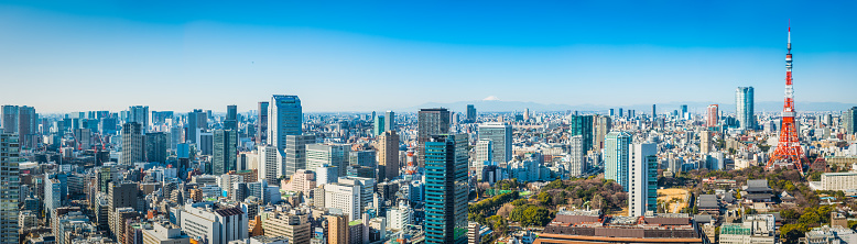 Clear blue skies above the crowded skyscraper cityscape of Tokyo, from the iconic snow capped summit of Mt. Fuji to the red and white spire of Tokyo Tower and the rooftops of Japan's vibrant capital city.
