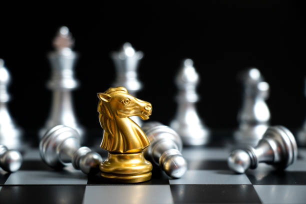 istock Gold horse in chess game face with the another silver team on black background (Concept for company strategy, business victory or decision) 938120036