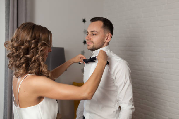 istock Bride fixes bow tie on groom s neck while they stand 938120120