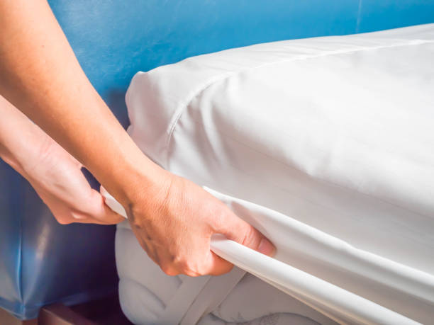 Woman is putting the bedding cover or mattress pad on the bed or putting off for cleaning process. stock photo