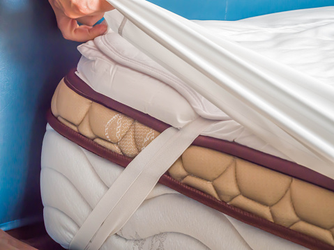 Mujer es poner la almohadilla de tapa o de colchón de cama en la cama o posponiendo para el proceso de limpieza. photo
