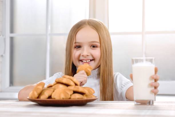 istock Cute little girl eats cookie with milk and smiling 938124852