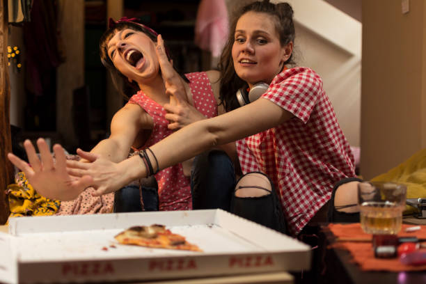 duas mulheres jovens lutando para o último pedaço de pizza. - beautiful white pink messy - fotografias e filmes do acervo