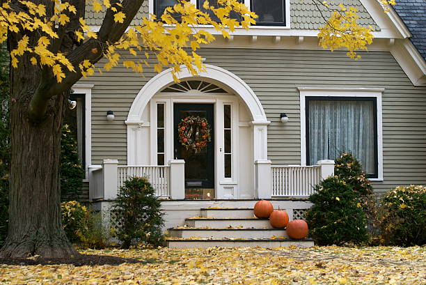 Rockville, MD, USA 11-01-2020: A two story wooden colonial era historic house in a well maintained garden in the historic district of Rockville. There are pumpkins and halloween decorations on porch