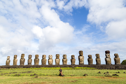 Easter Island, Chile - December 3, 2015: Tourist sitting in front of the 15 moais at Ahu Tongariki