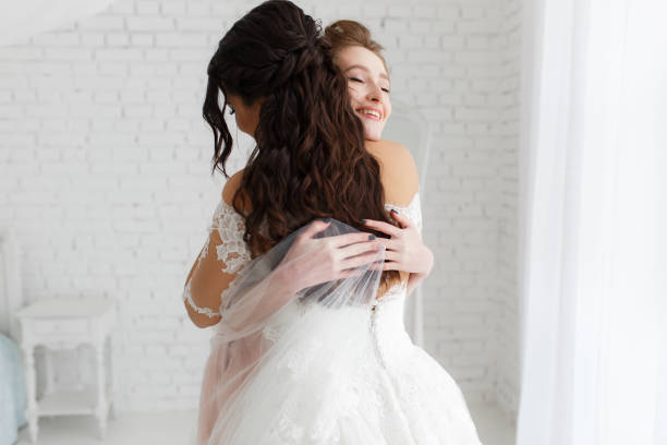 istock luxury bride hugging bridesmaid and smiling, joyful moment in minimalistic loft white brick background 938136626