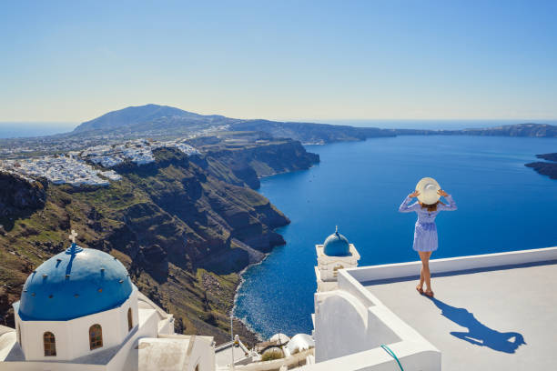 Young woman  looks at the marine landscape Young woman stands on a hill and looks at the marine landscape of Santorini, Greece greek islands stock pictures, royalty-free photos & images