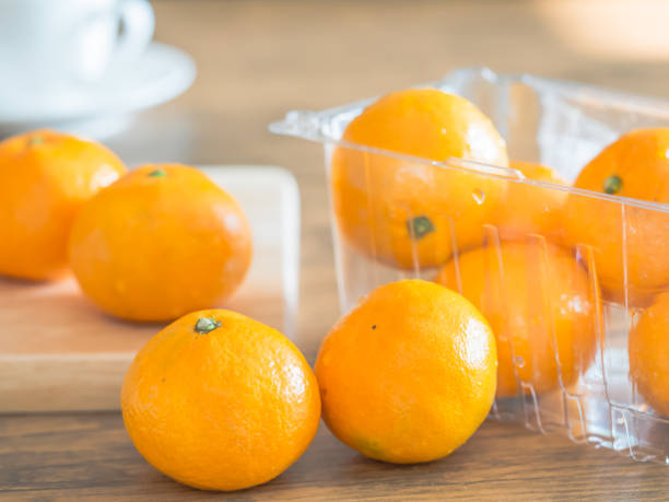 istock Oranges, wooding cutting board on the table in the kitchen with blurry white coffee cup background. Dieting or healthy concepts. 938138428