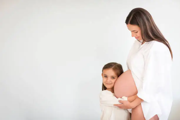 Photo of Young pretty pregnant woman and her little daughter