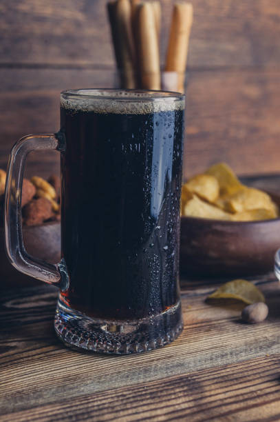 istock Dark beer in a mug. Snacks for beer on a wooden table. Chips, croutons, bread sticks 938146008