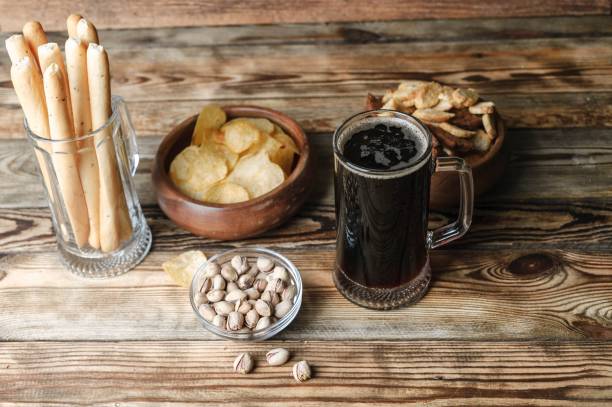 istock Dark beer in a mug. Snacks for beer on a wooden table. Chips, croutons, bread sticks 938146048