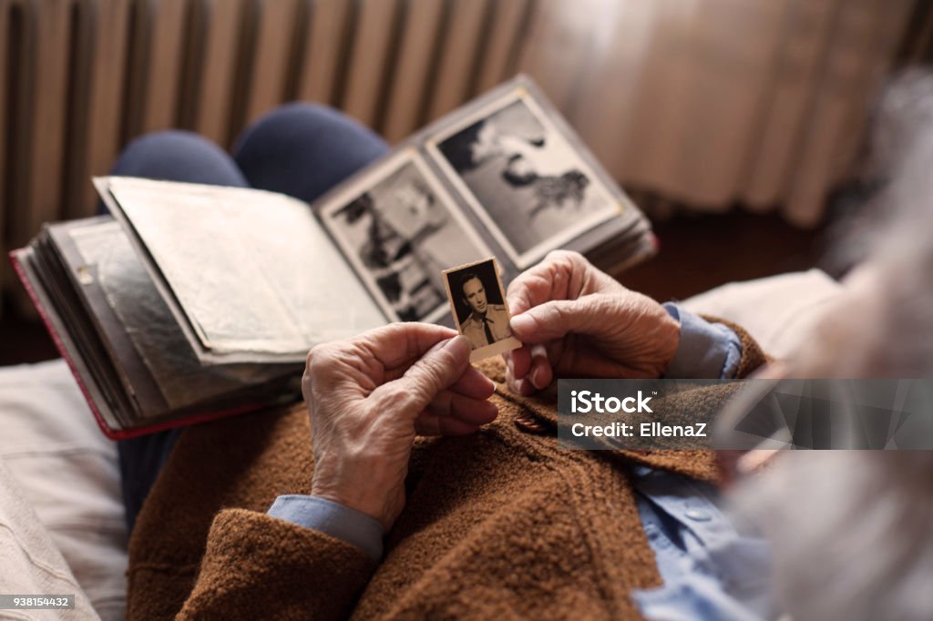 Memories. Senior adult woman looking at an old photo of her husband. Photograph Stock Photo
