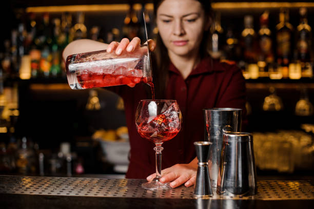 istock Bartender girl pouring a delicious light red cocktail 938154712