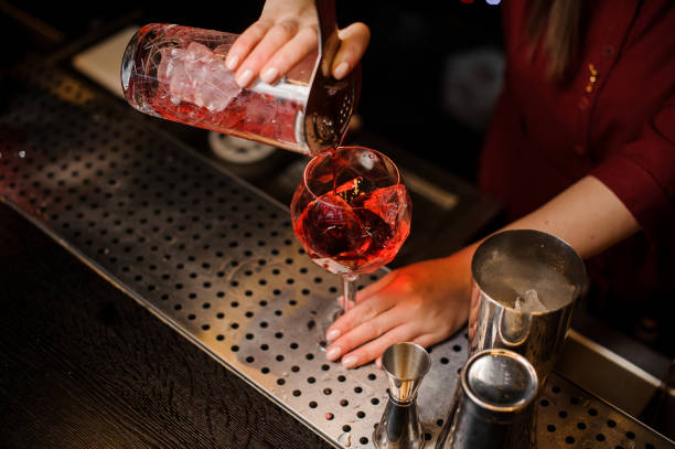 Bartender girl pouring a fresh campari cocktail