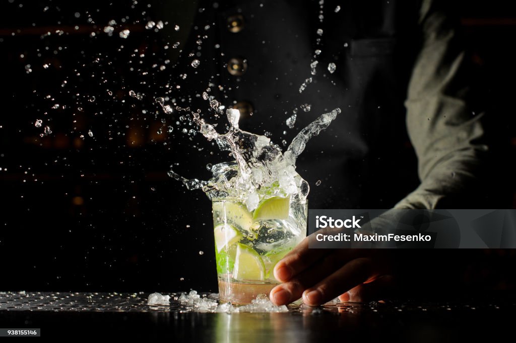 Cocktail splash with ice cubes and lime Cocktail splash with ice cubes and lime. Preparing of the delicious fresh cocktail on the bar stand Cocktail Stock Photo