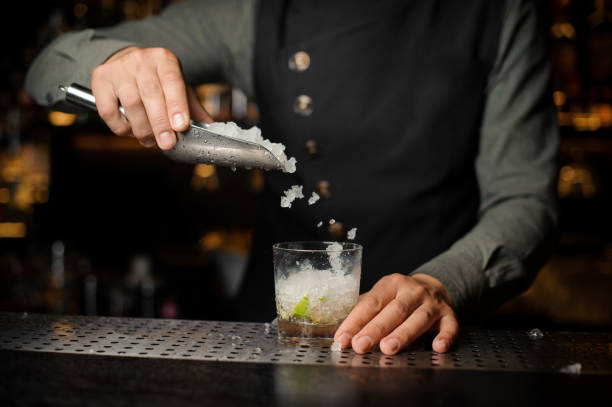 istock Barman adding an ice into the glass with a cane sugar and lime 938155260