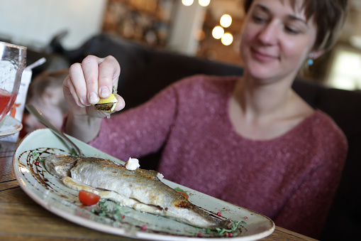 Woman eating fried trout in a restaurant