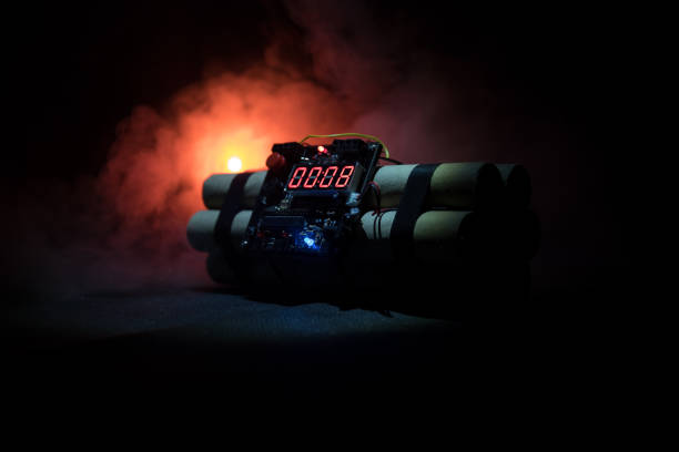 istock Image of a time bomb against dark background. Timer counting down to detonation illuminated in a shaft light shining through the darkness 938165846