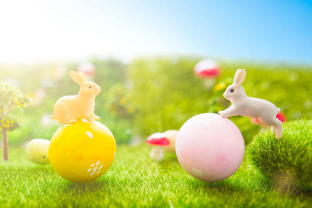istock Happy Easter concept. Easter rabbits toy on spring green grass. Fairy tale sunset on the plastic green field with plastic grass, mushrooms and trees. Fake grass. Macro 938166472