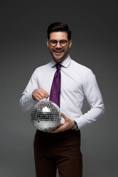 istock Smiling businessman holding glass disco ball isolated on grey 938167664