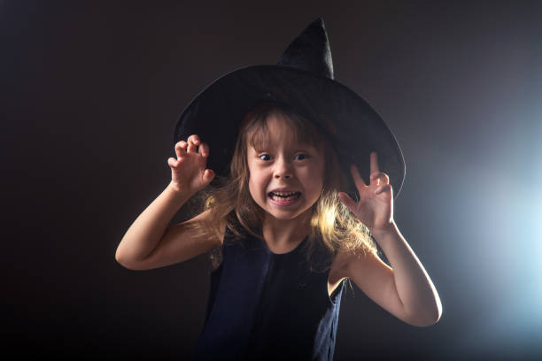 istock Beautiful girl in a witch hat on a dark background with free space for your text. 938170742