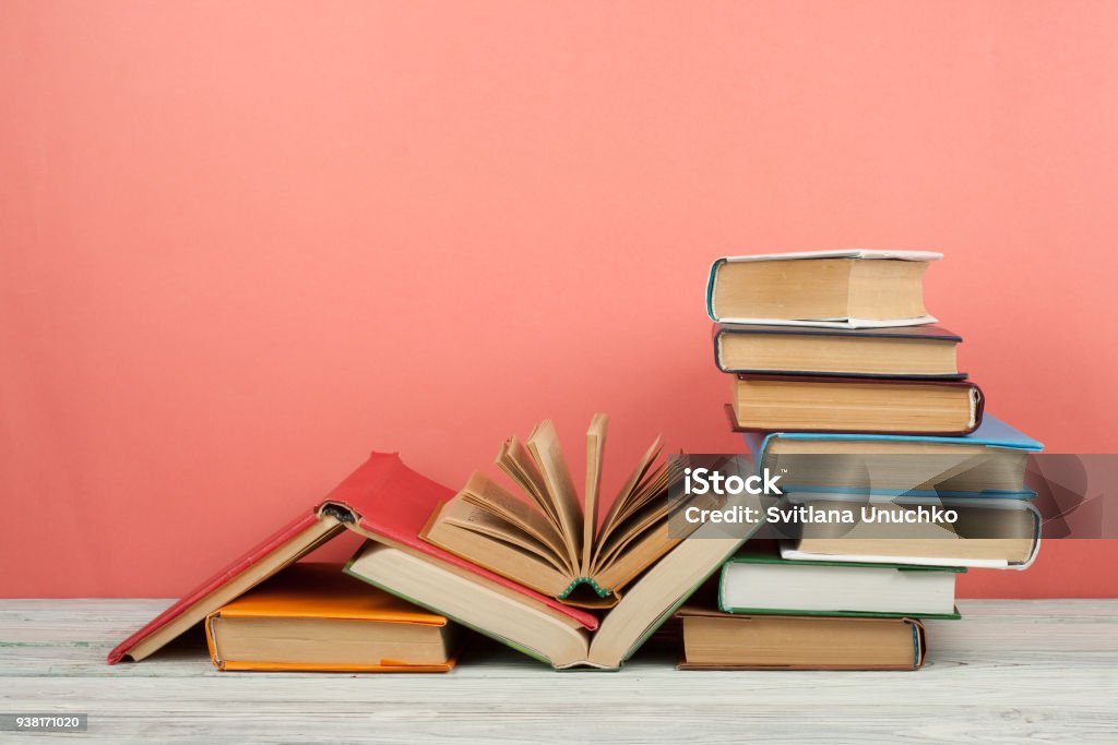 Book stacking. Open book, hardback books on wooden table and pink background. Back to school. Copy space for text Book stacking. Open book, hardback books on wooden table and pink background. Back to school. Copy space for text. Book Stock Photo