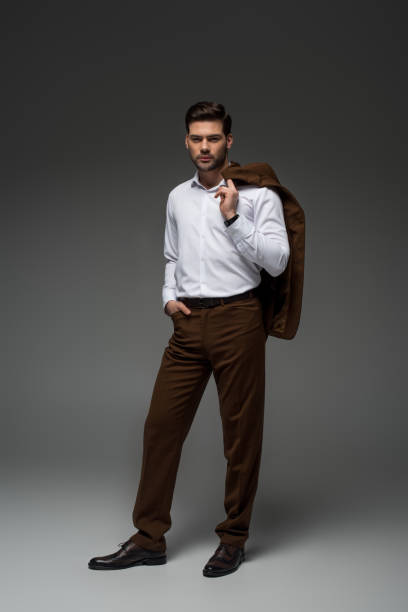 istock Young businessman holding jacket on shoulder on grey 938174670