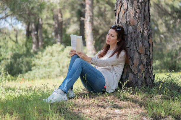istock Beautiful women sitting in forest and reading book 938177784