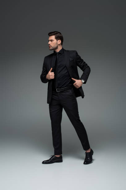 istock Young stylish man posing in formal suit on grey 938179178
