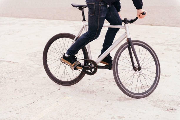 istock Man's legs wearing jeans riding fix bike 938182080