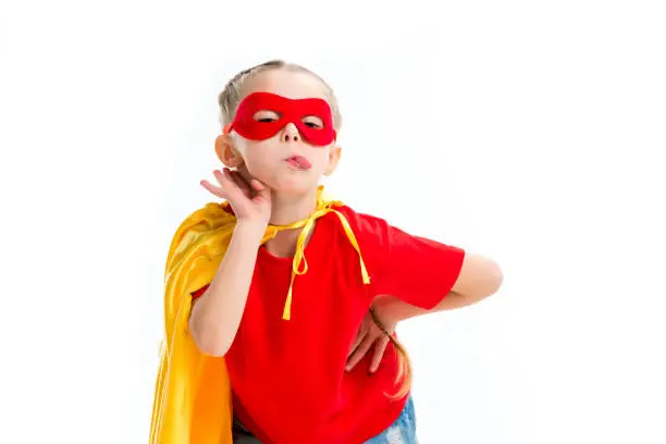 Supergirl wearing yellow cape and red mask for eyes showing tongue isolated on white