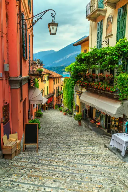 Amazing old narrow street view, famous picturesque cobblestone street with souvenir shops, restaurants and cafes in Bellagio touristic resort, Lake Como, Italy, Europe