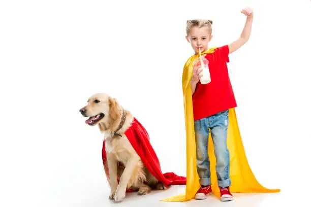 Supergirl drinking milkshake and gesturing with dog in red cape beside isolated on white