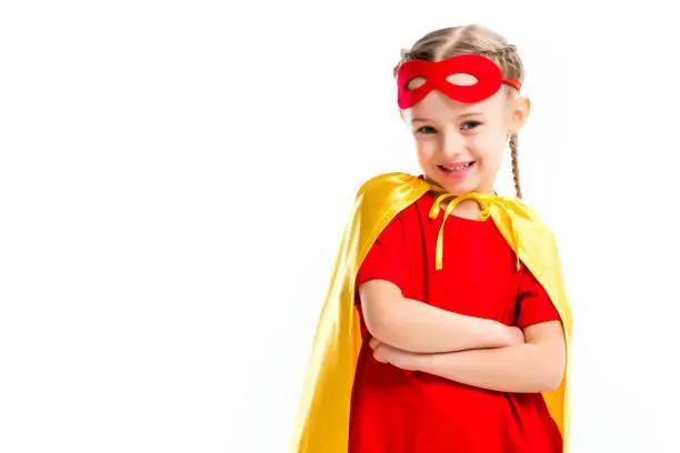 Excited little supergirl wearing yellow cape with red mask for eyes on forehead  isolated on white