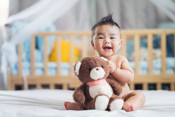 Asian baby sit with teddy bear Asian baby sit with teddy bear on ther bed in bedroom bedtime photos stock pictures, royalty-free photos & images
