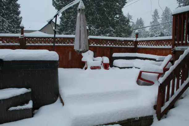 A backyard patio and hot tub covered in snow"n