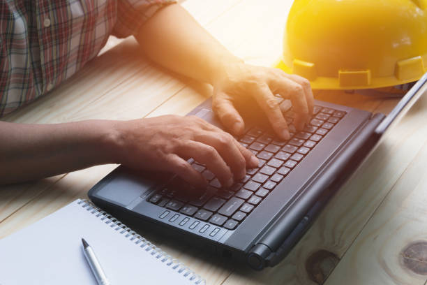 Architect engineer using laptop for working with yellow helmet on table. stock photo