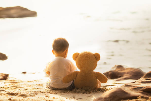 istock Baby and teddy bear sit togather on the beach 938204866